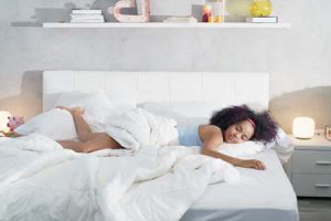 black-woman-sleeping-alone-in-large-bed-NF5HJ2E